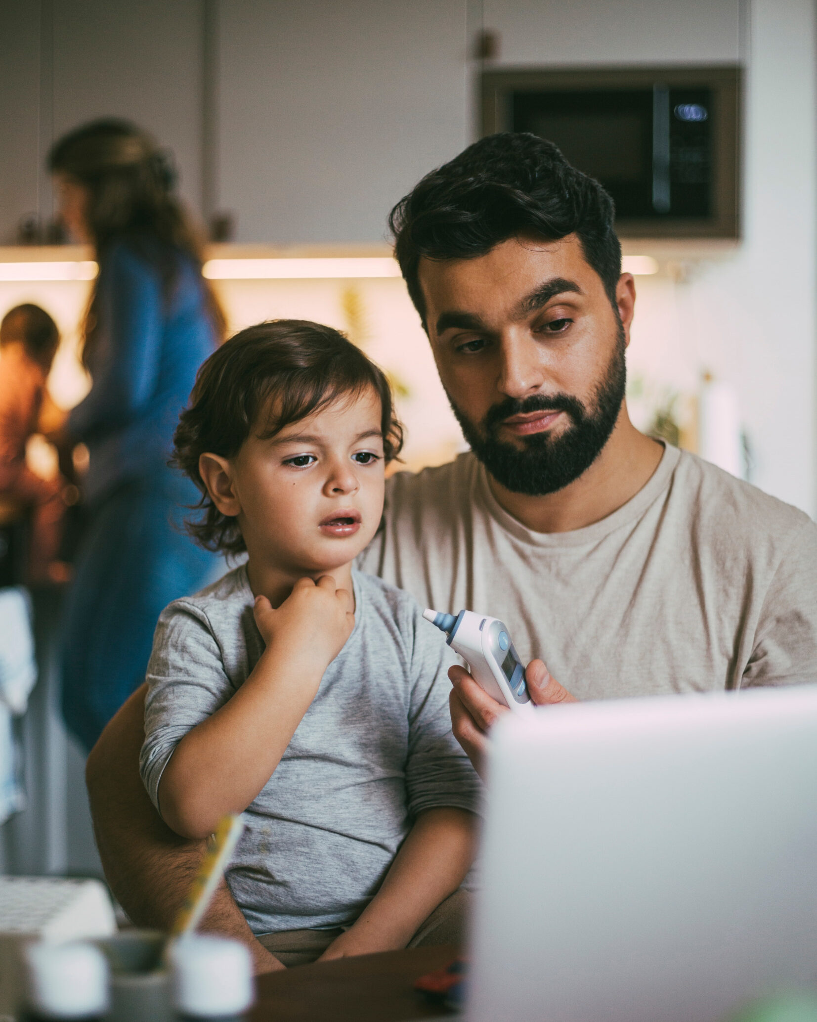 Child sitting on his fathers lap by a kitchen table