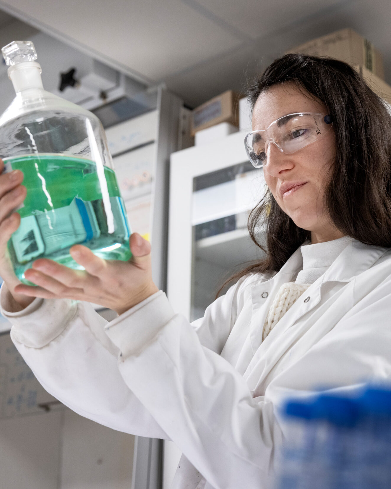 Woman in a lab holding a large vial.