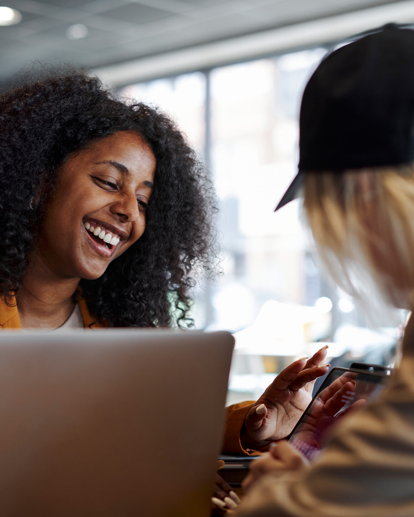 Two people sit across from each other at a desk, looking at a shared mobile device..